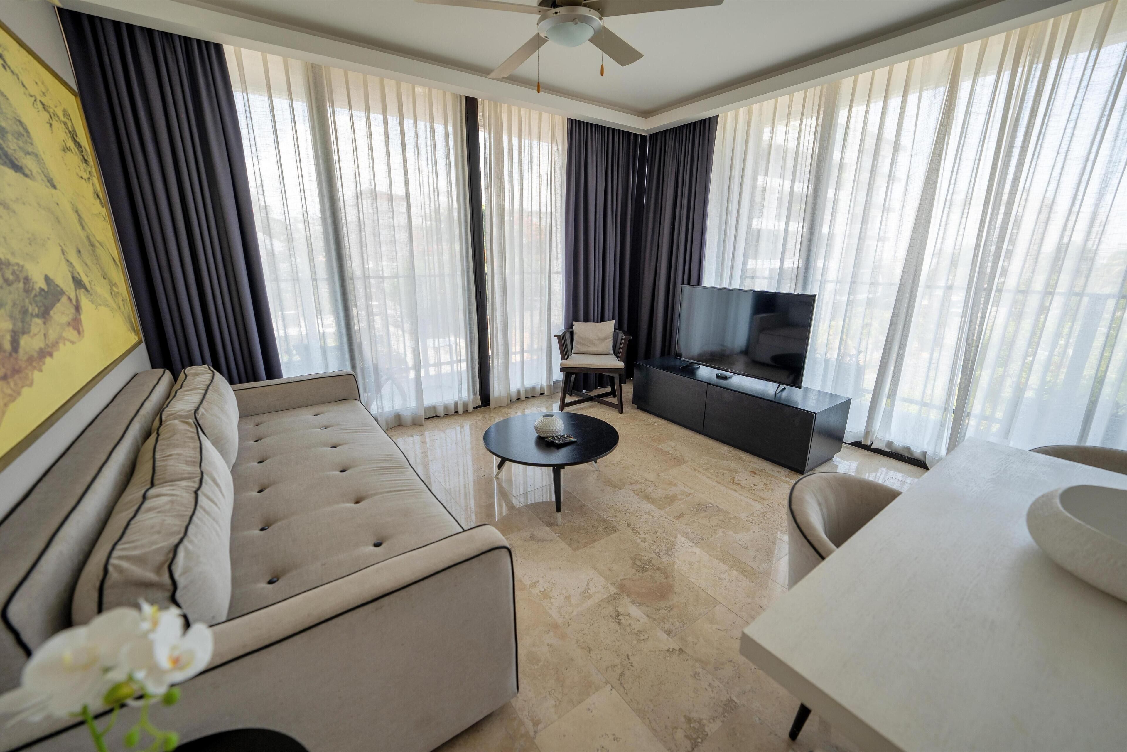 A modern living room with a sofa, a coffee table, a TV, and a dining area.