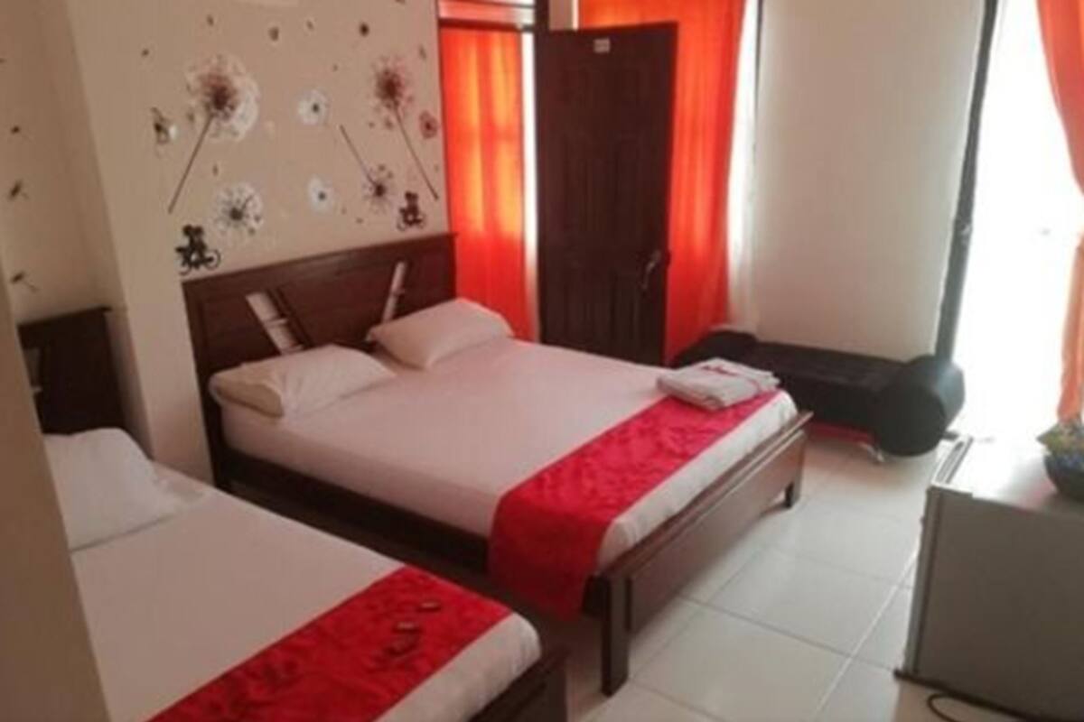A hotel room with two beds, a desk, and a wardrobe.