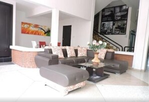 A modern living room with a sectional sofa, a coffee table, and a fireplace. - Hotel Cartago Plaza (Cartago)