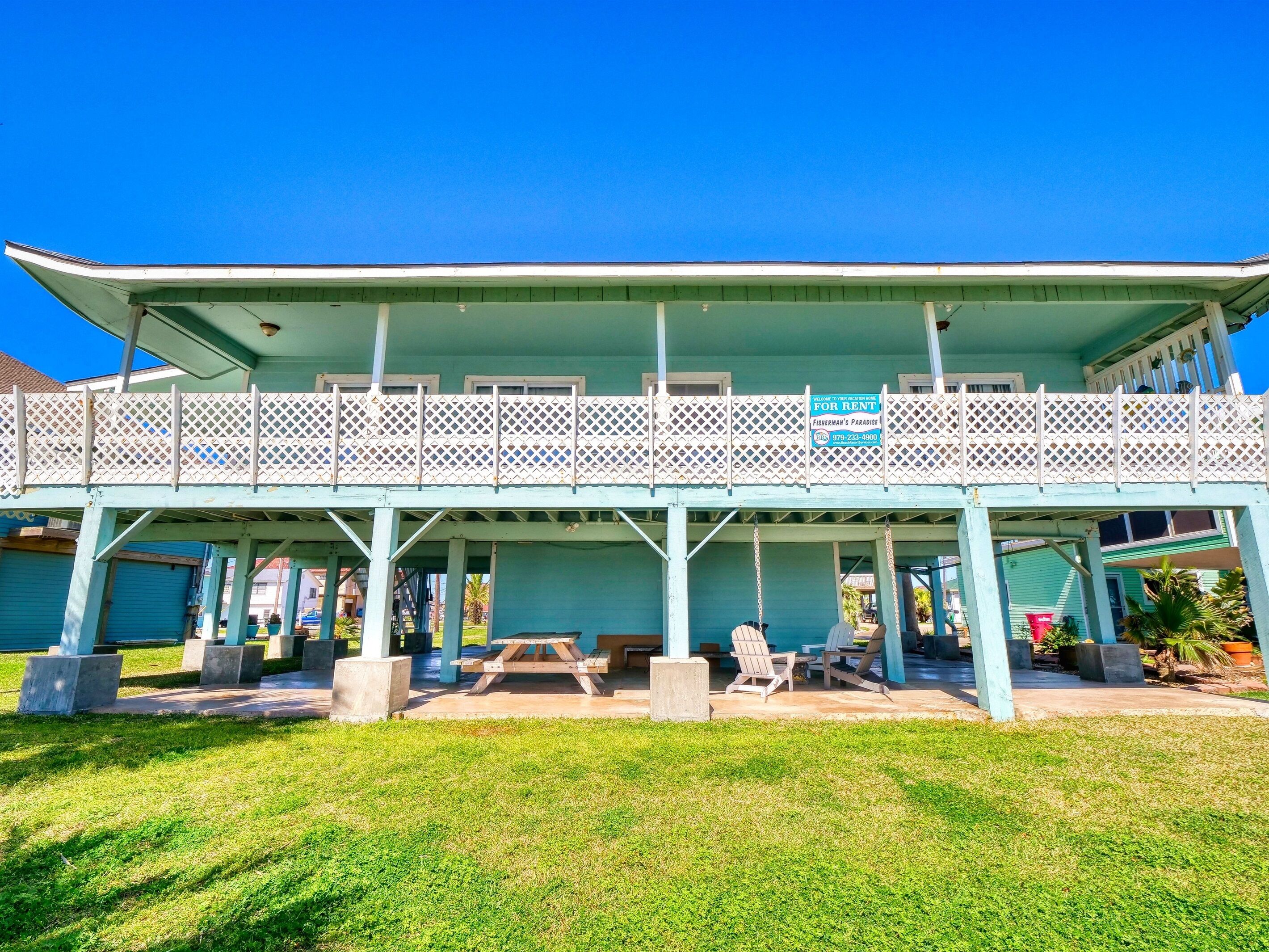 A two-story building with a balcony, a picnic table, and outdoor seating.