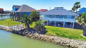 Une propriété située sur la côte, comprenant une grande maison, un quai et un muret en pierre au bord de l’eau.