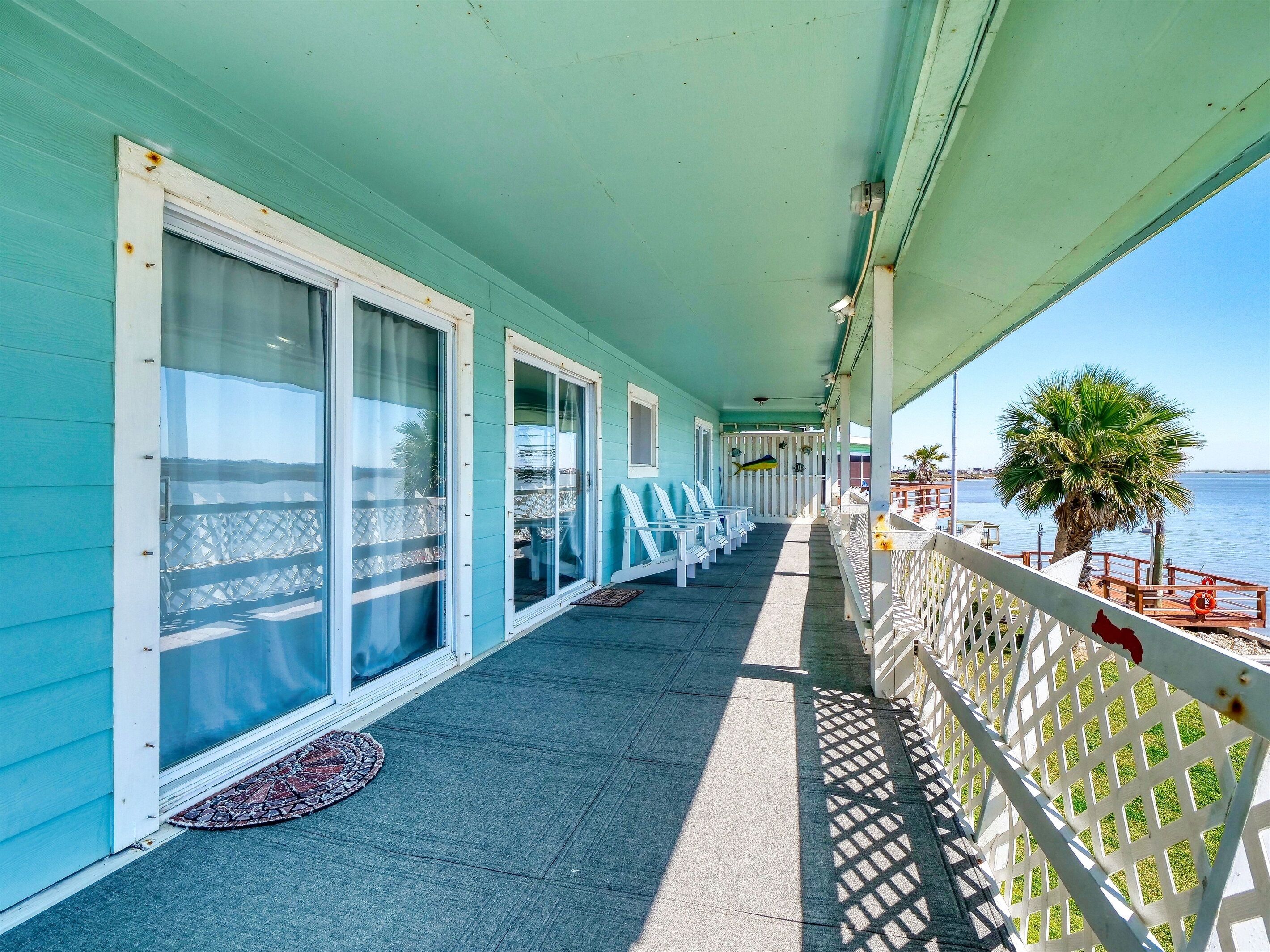 Un balcone coperto con vista sul mare, con una fila di sedie e un tavolino.