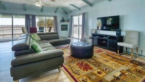 Un salon spacieux avec un grand canapé, un pouf et un meuble pour l’équipement audiovisuel.