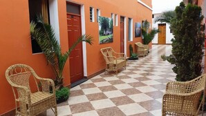 A corridor with wicker chairs, a checkered floor, and a building with an orange facade. - Hostal Characato Suite (Arequipa)