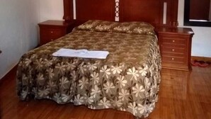 A bedroom with a wooden bed, a nightstand, a dresser, and a framed picture on the wall. - Hostal Characato Suite (Arequipa)