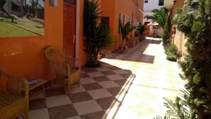 A corridor with checkered flooring, wicker furniture, and potted plants. - Hostal Characato Suite (Arequipa)