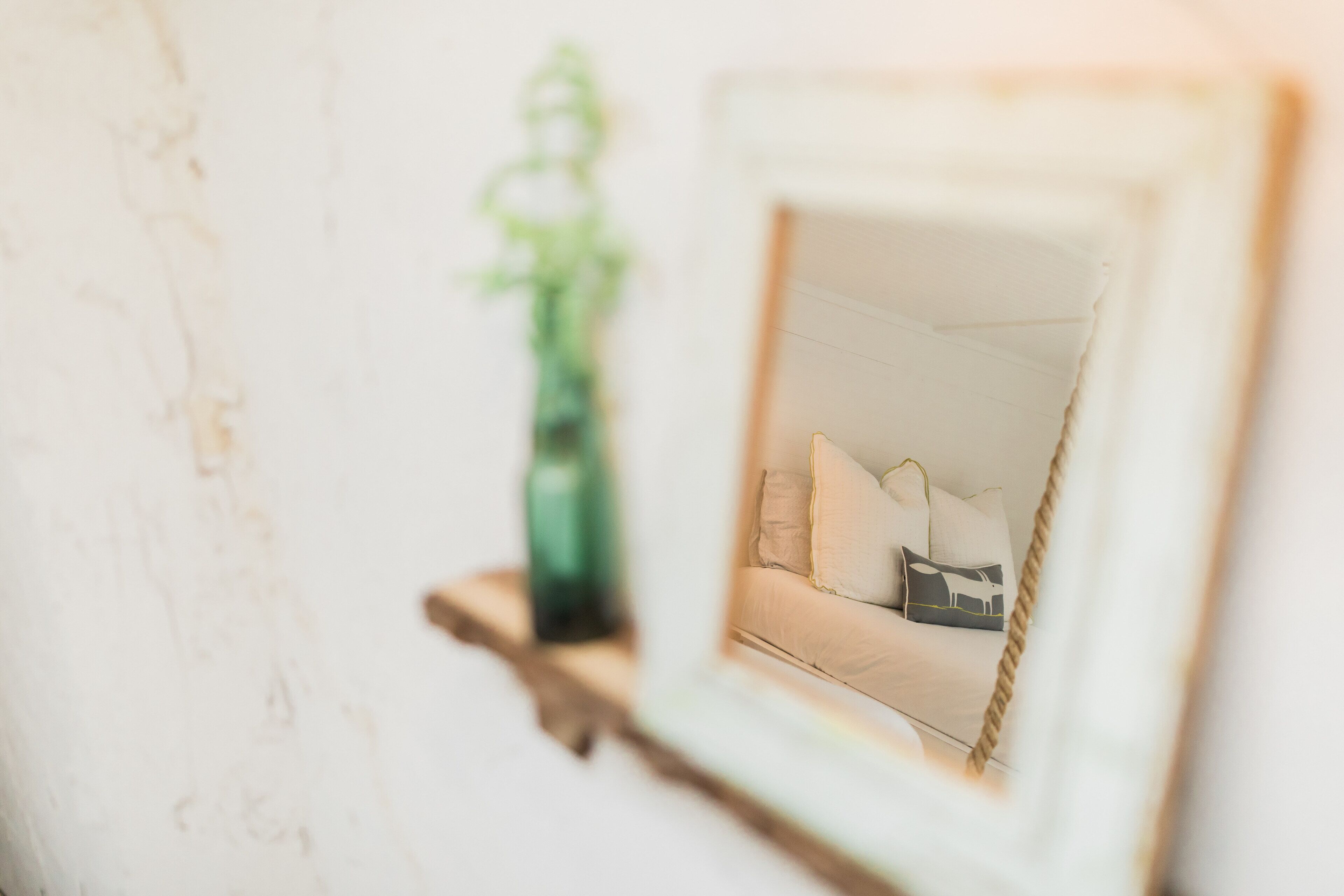A framed picture of a bed with pillows and a bedside table.