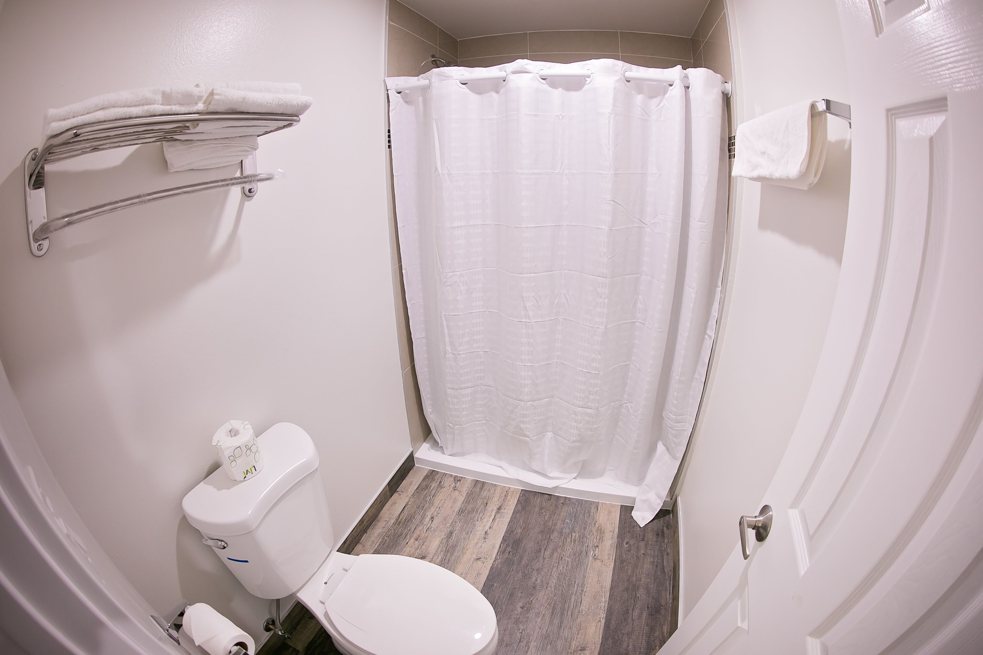 Un baño pequeño y limpio con inodoro, cortina de ducha y toallero.