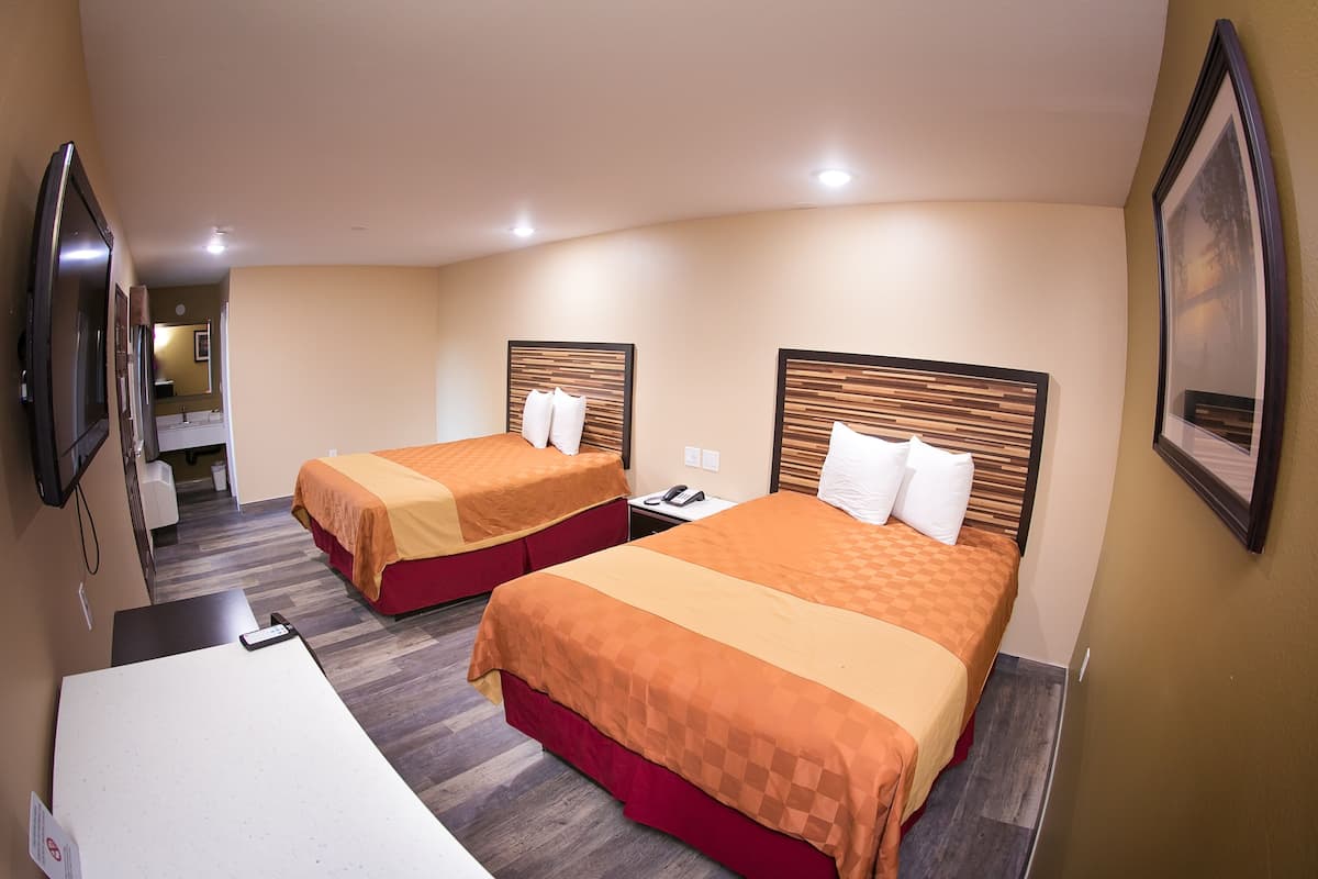 A hotel room with two beds, a desk, and a mirror.