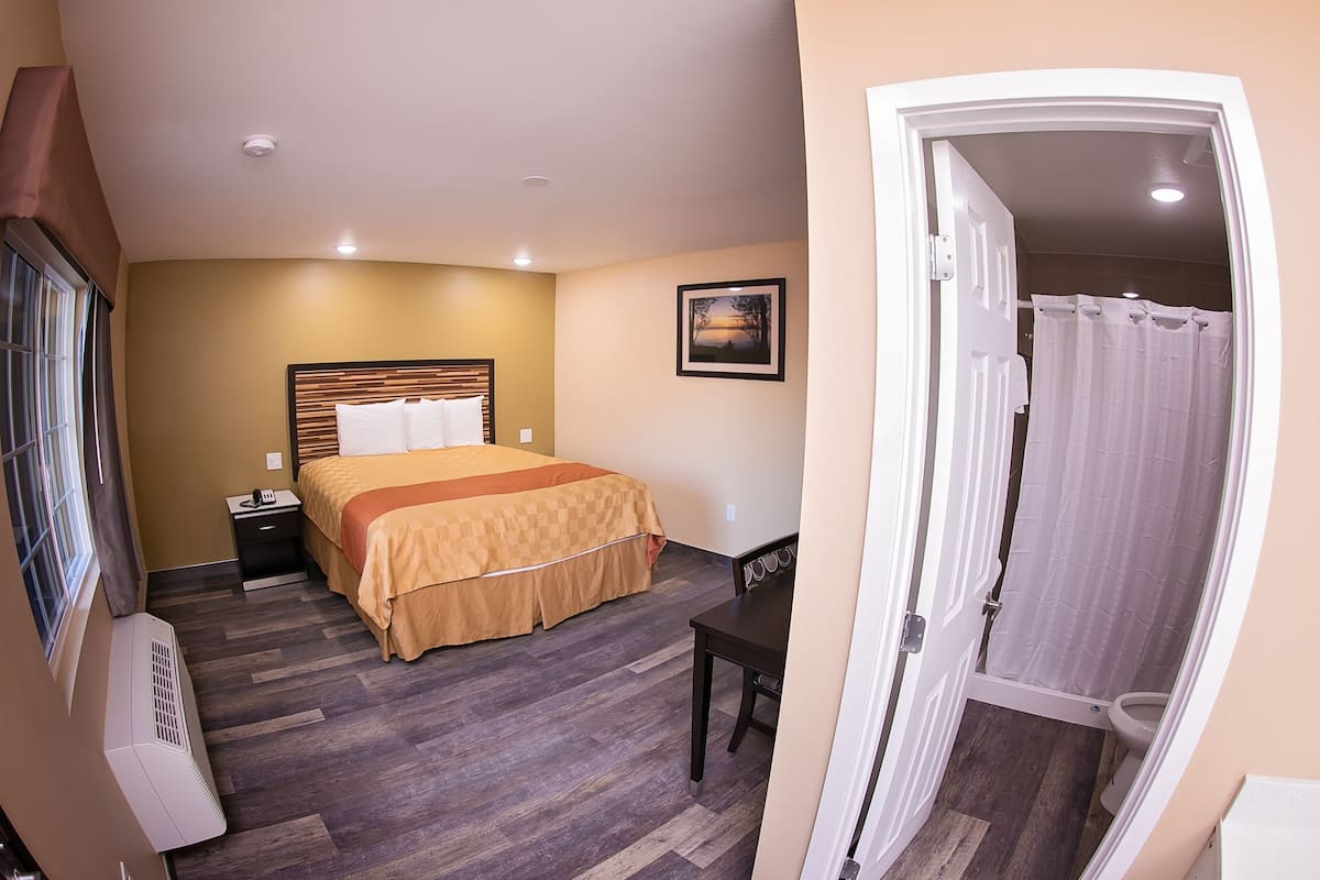 A hotel room with a bed, bedside table, and a view of the bathroom.