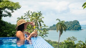 A person relaxing in a pool with a view of a tropical landscape and a body of water. - Vista Oceana, Stunning Ocean View Villa (Quepos)