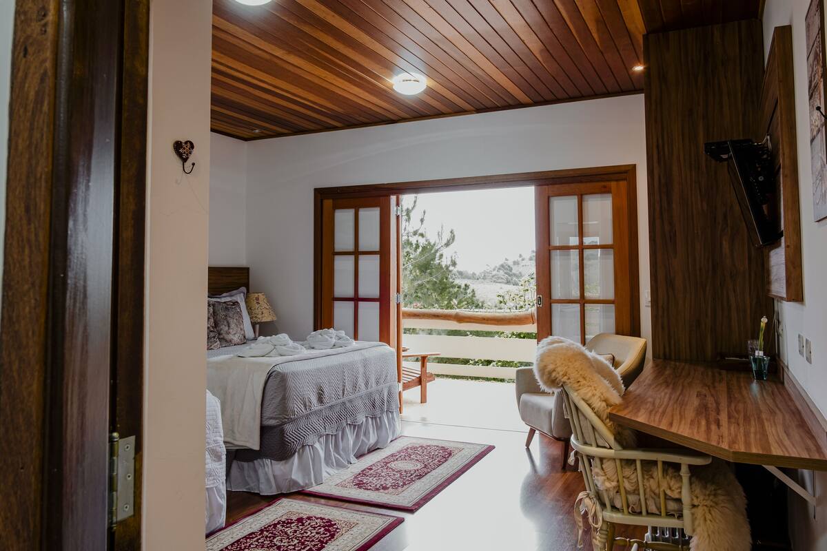 Un dormitorio con cama, una silla, una mesa y un balcón con vistas.