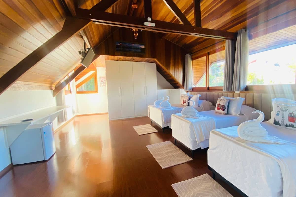 Habitación de hotel con dos camas, suelo de madera, un escritorio pequeño y vistas al exterior.