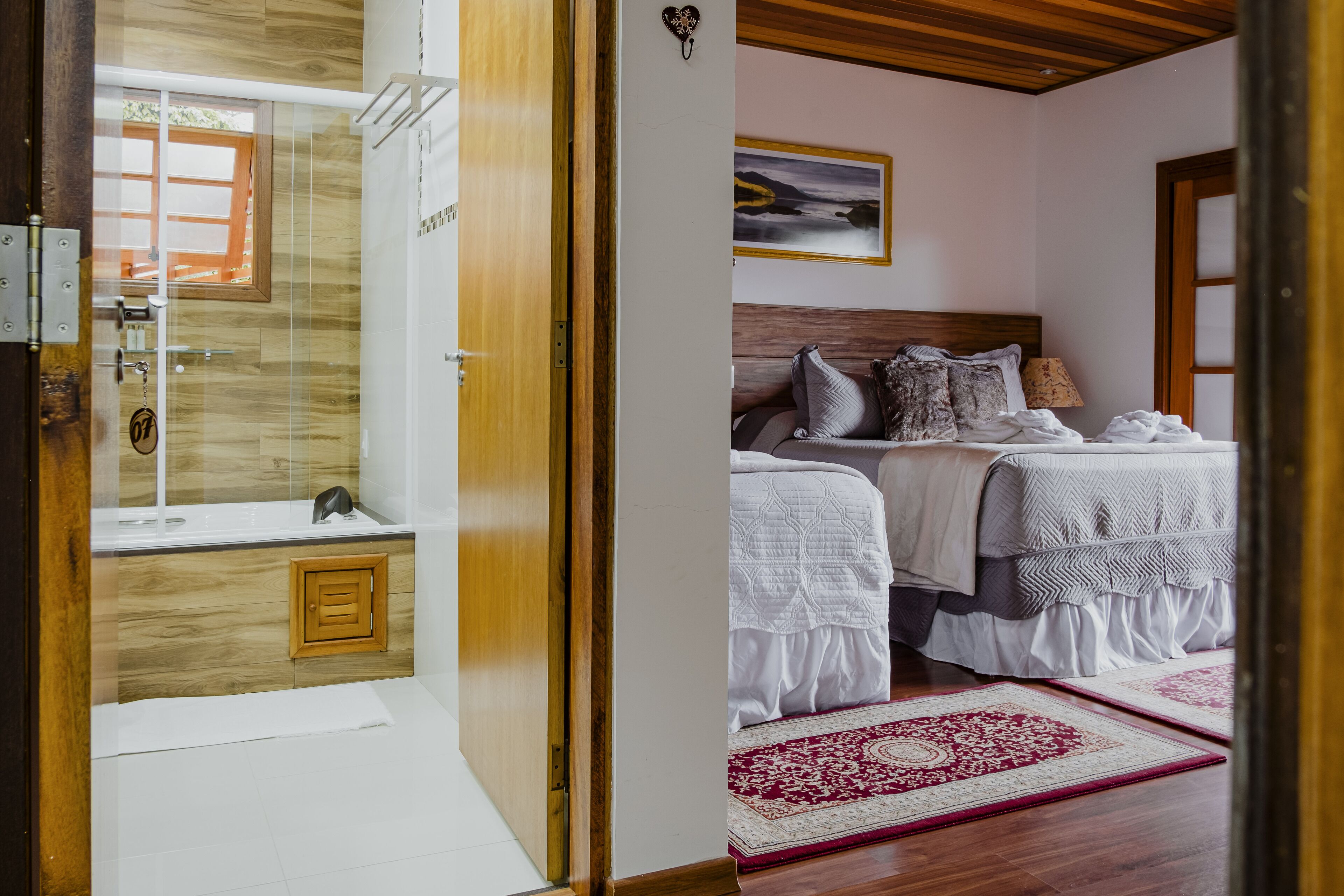 A bathroom with a wooden vanity, a shower, and a glass-enclosed toilet.