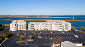 Ein mehrstöckiges Hotel mit Parkplatz davor, in der Nähe von Gewässer, im Hintergrund eine Brücke.