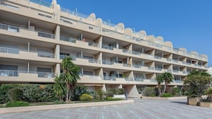 Um hotel com vários andares, varandas, um pátio pavimentado e áreas verdes ajardinadas.