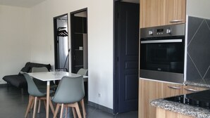 A modern kitchen with a built-in oven and a dining area with a table and chairs. - Charming Small Villa Any Comfort Ideal 4 People 2bedroom close Tizzano (Sartène)