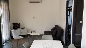 A modern living room with a white table, grey chairs, a grey sofa, and a TV on a cabinet. - Charming Small Villa Any Comfort Ideal 4 People 2bedroom close Tizzano (Sartène)