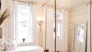 Une chambre à coucher avec un lit, un luminaire suspendu et un grand miroir.