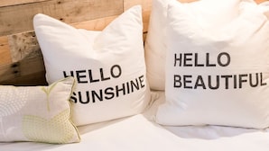Deux oreillers blancs, ornés de motifs, sont posés sur un lit adossé à une tête de lit en bois.