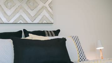 A neatly made bed with patterned pillows and a bedside lamp.