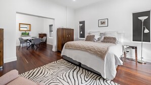 A spacious bedroom with a large bed, a desk with chairs, and a wardrobe.