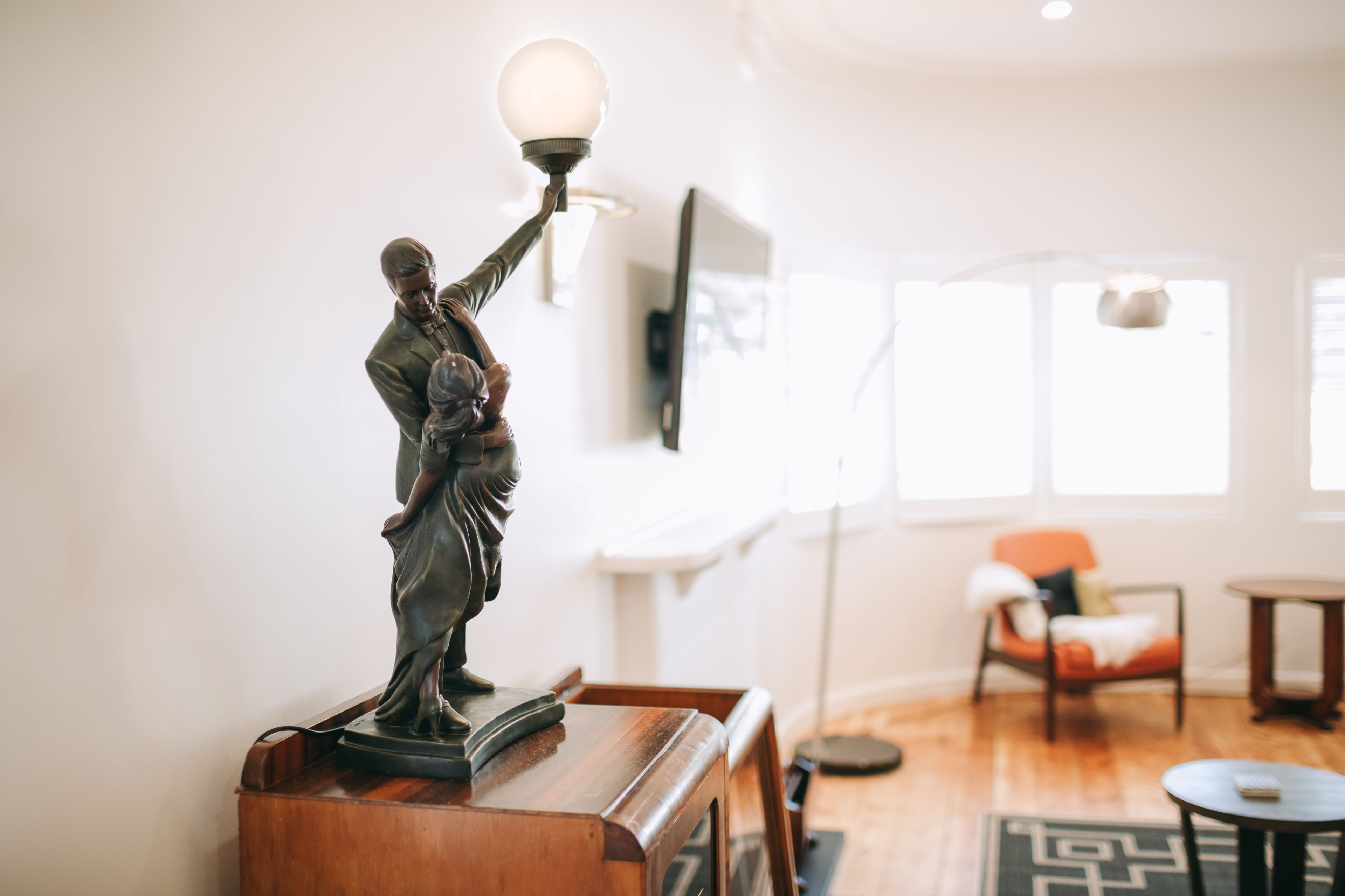 A statue on a wooden table in a well-lit room with a modern interior, including a sofa and a coffee table.
