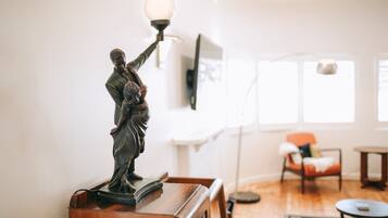A statue on a wooden table in a well-lit room with a modern interior, including a sofa and a coffee table.