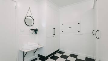 A bathroom with a black and white checkered floor, a white sink with a mirror above it, and a small shelf with towels.