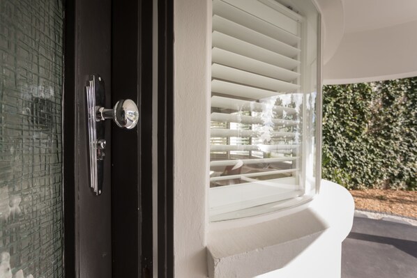 Una puerta con un panel de vidrio y una ventana con persianas blancas.