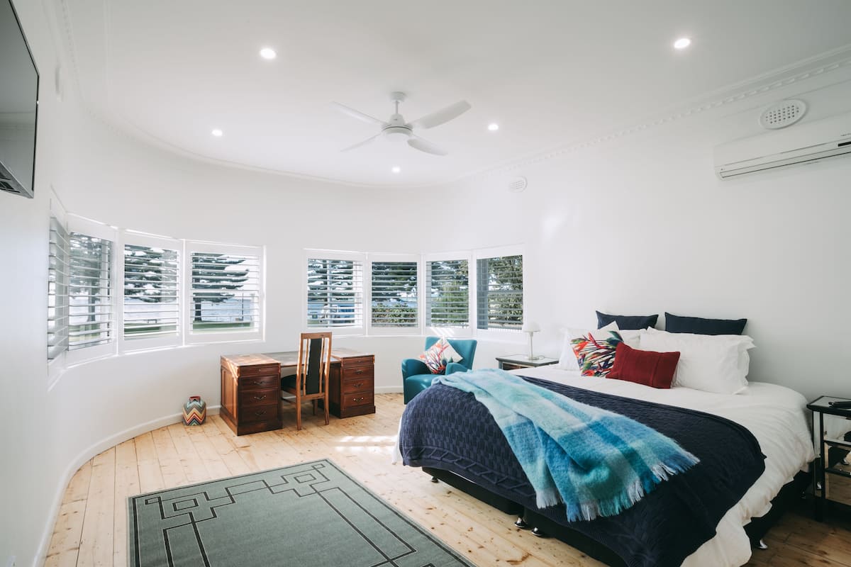 A bedroom with a bed, a desk, a chair, and a window.