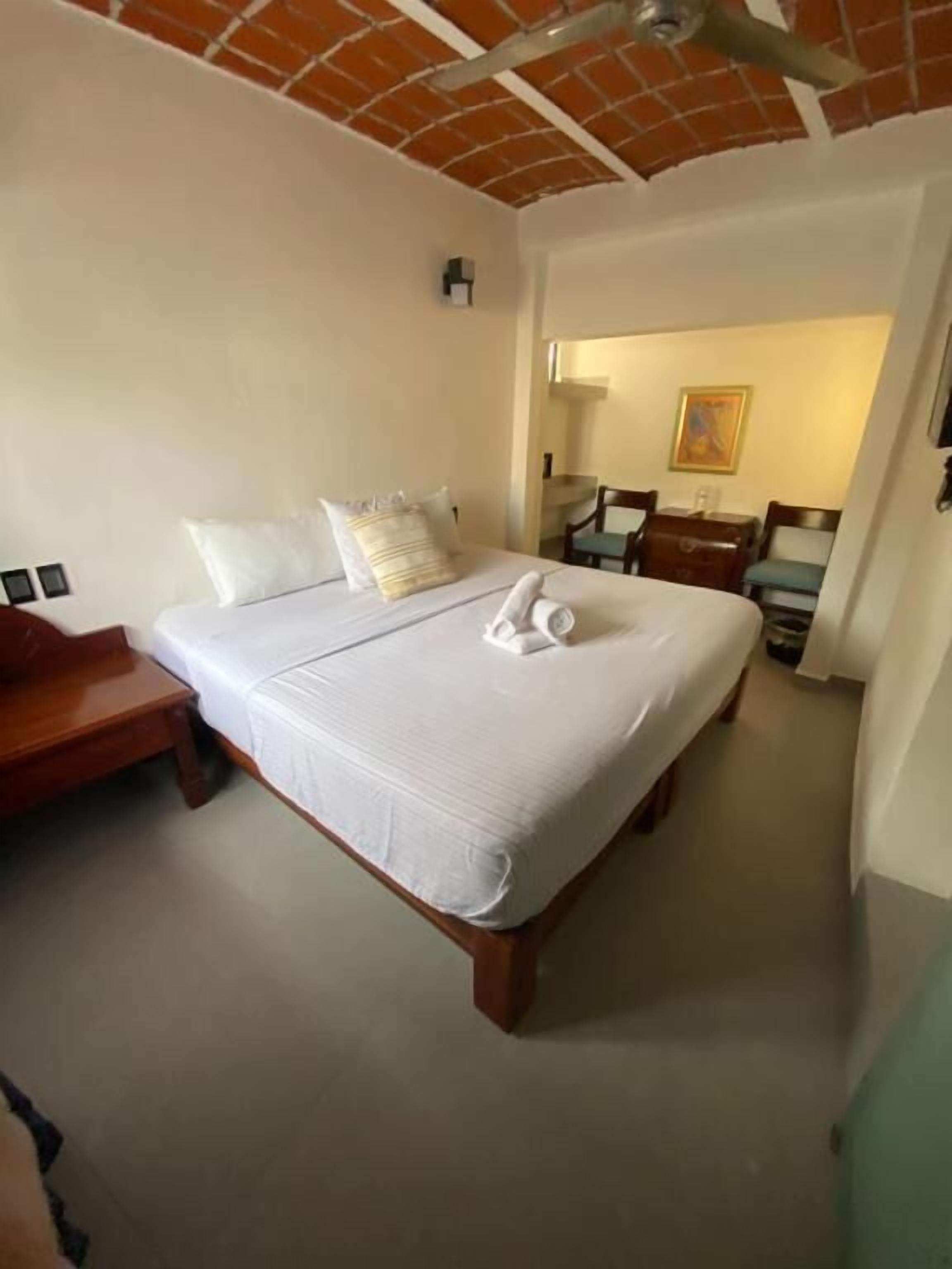 Une chambre d’hôtel avec un grand lit, une table de chevet en bois, un bureau et une chaise.