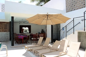 An outdoor patio with lounge chairs, a dining table, and an umbrella.