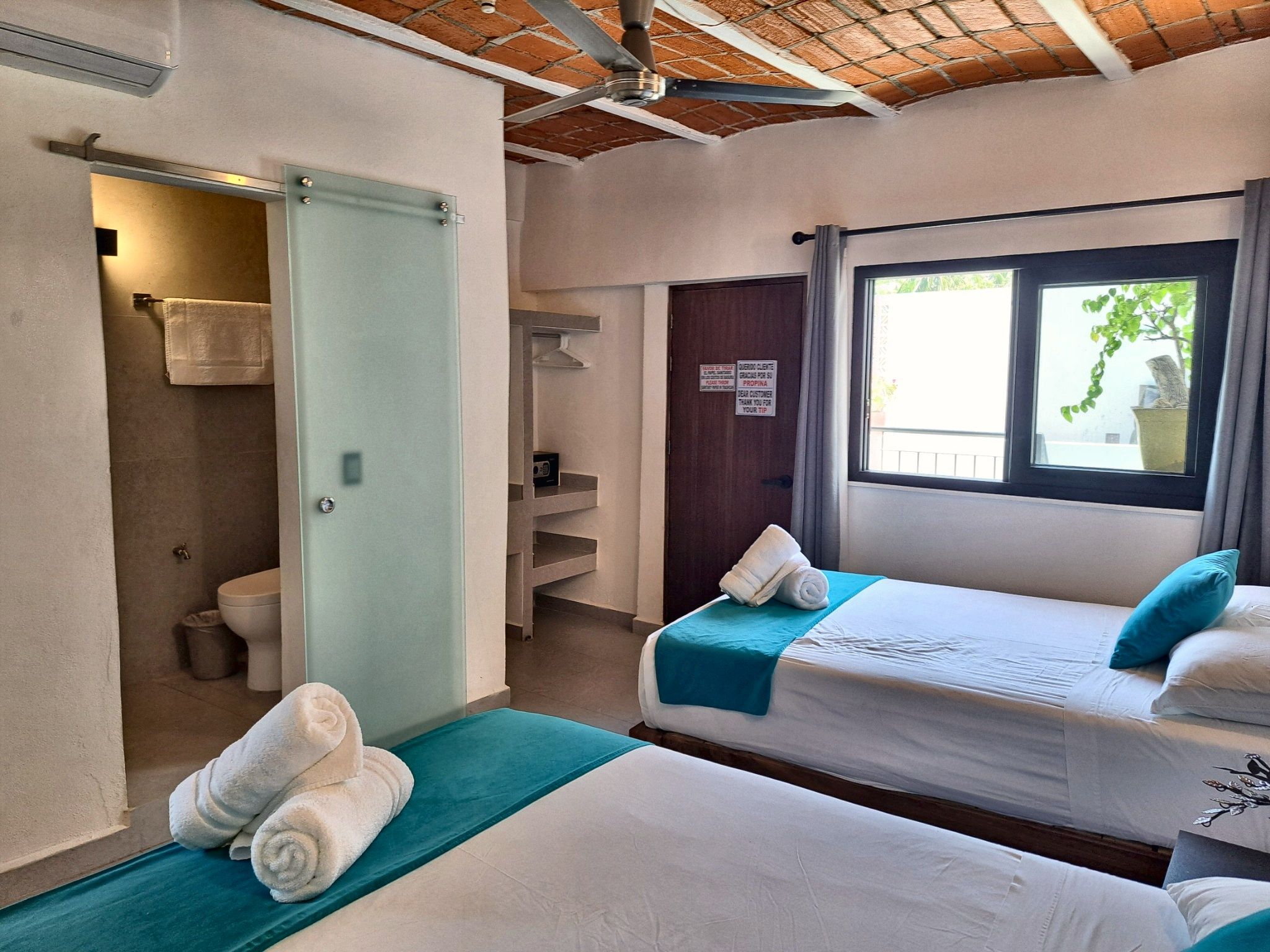 Habitación de hotel con dos camas, baño y ventana con vistas.