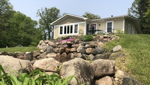 A house with a stone retaining wall, a small pond, and a grassy area. - Beautiful Get Away for any season only ONE Hour from the Twin Cities! (Zimmerman)