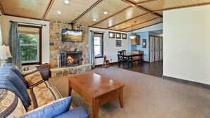 A spacious living room with a stone fireplace, a wooden ceiling, and a cozy seating area. - Beautiful Get Away for any season only ONE Hour from the Twin Cities! (Zimmerman)