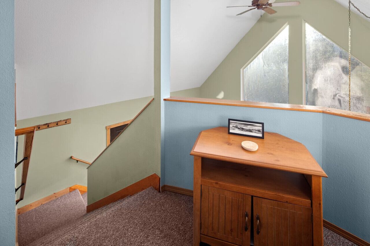 A room with a wooden cabinet, a framed picture, and a window with a view of a tree.