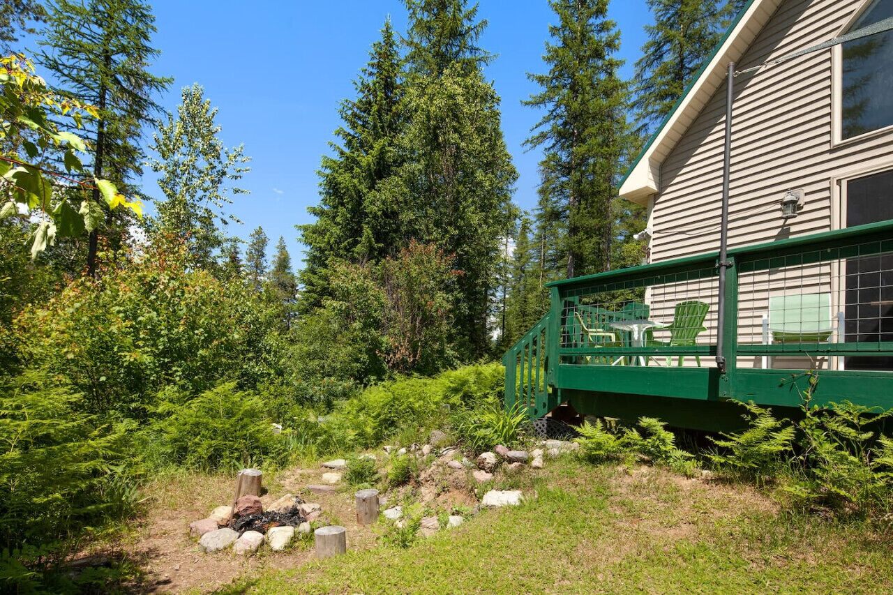 Une maison dotée d’une terrasse verdoyante, entourée d’une végétation luxuriante et d’arbres.