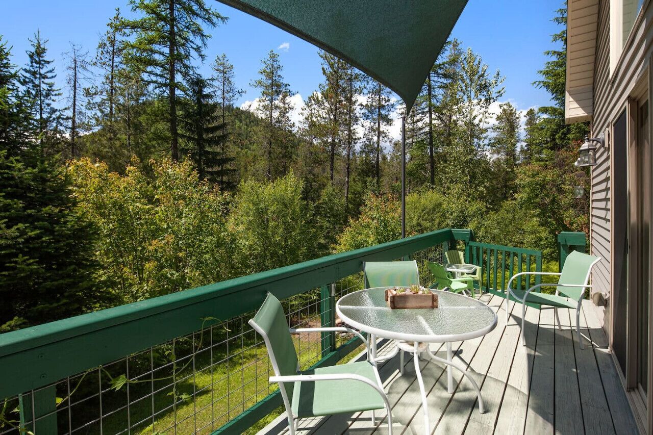 Un balcon avec une balustrade verte, une table ronde et deux chaises.