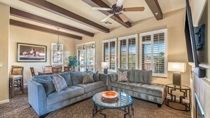 A living room with a sectional sofa, a glass coffee table, and a ceiling fan.