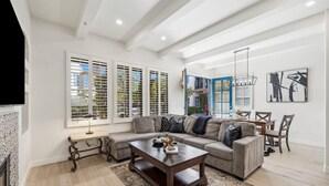 A spacious living room with a large sectional sofa, a wooden coffee table, and a dining area with a table and chairs.