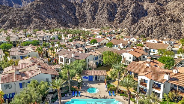 A resort with multiple buildings, a swimming pool, and palm trees.