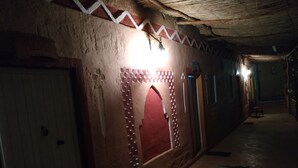 A corridor with a patterned wall, a red archway, and a striped carpet. - Riad Dar Zaouia (Zagora)
