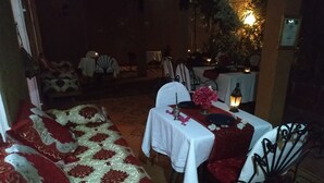 A cozy dining area with a sofa, tables, chairs, and a lantern. - Riad Dar Zaouia (Zagora)