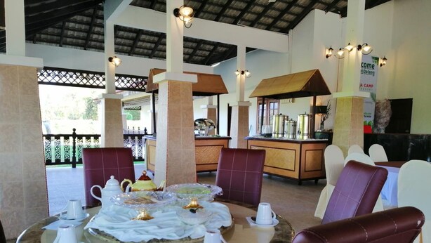 A dining area with a round table set for four, surrounded by cushioned chairs. - AsiaCamp Resort (Kuala Tembeling)
