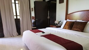 A neatly made bed with a white and red bedspread, a wooden headboard, and patterned pillows. - AsiaCamp Resort (Kuala Tembeling)