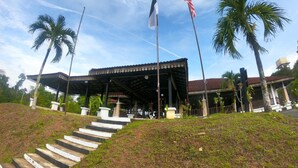 A building with a covered entrance, palm trees, and two flags. - AsiaCamp Resort (Kuala Tembeling)