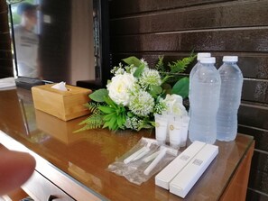 A reception desk with a wooden box, a bouquet of white flowers, two water bottles, and toiletries.