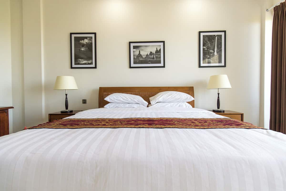 A hotel room with a large bed, two bedside tables, and three framed pictures on the wall.