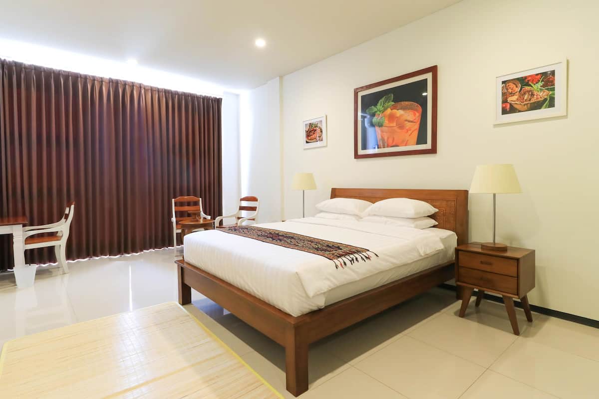 A neatly arranged hotel room with a bed, bedside tables, a desk, and chairs.